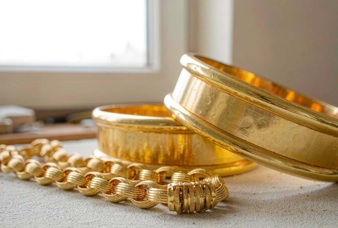 Heavy 22K gold bangles and a high-karat gold chain on a goldsmith's workbench